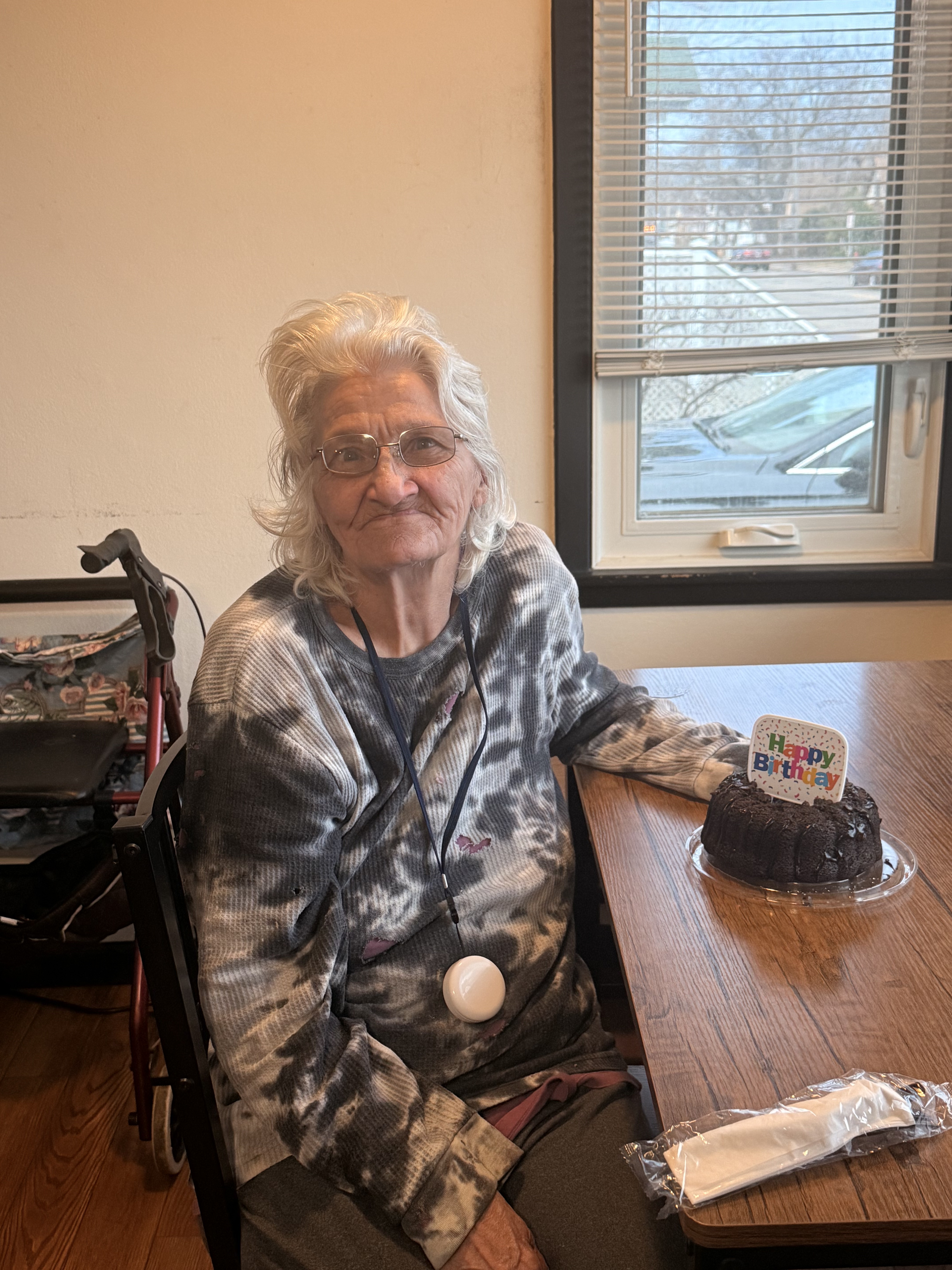 A resident sitting at the dining table beside her birthday bundt cake